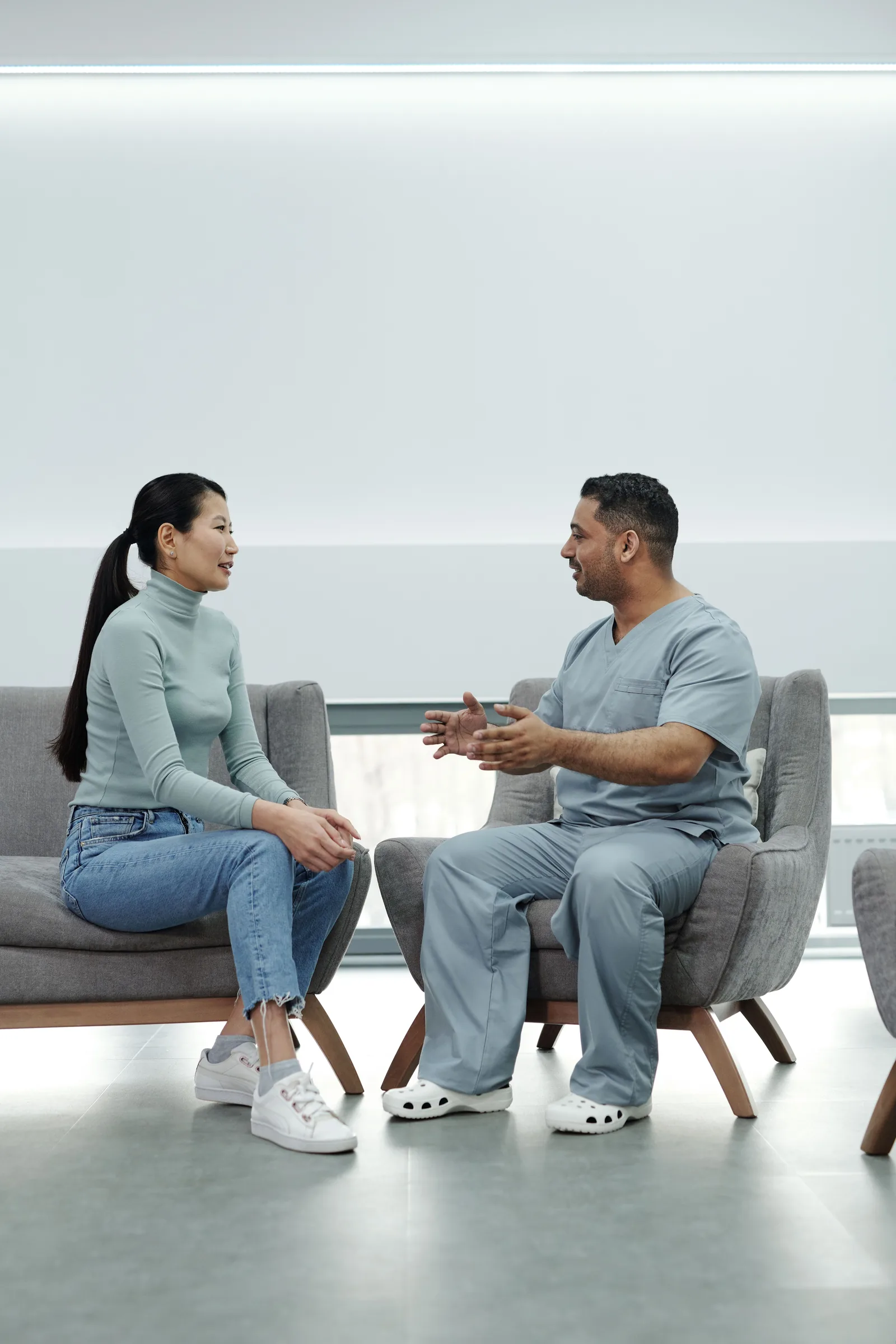 A patient and healthcare worker talking in a bright clinic waiting area