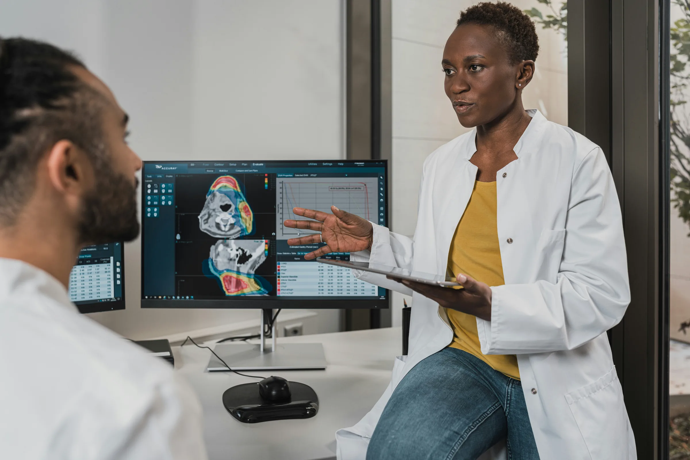 A clinician explaining medical imaging data on screen to a colleague